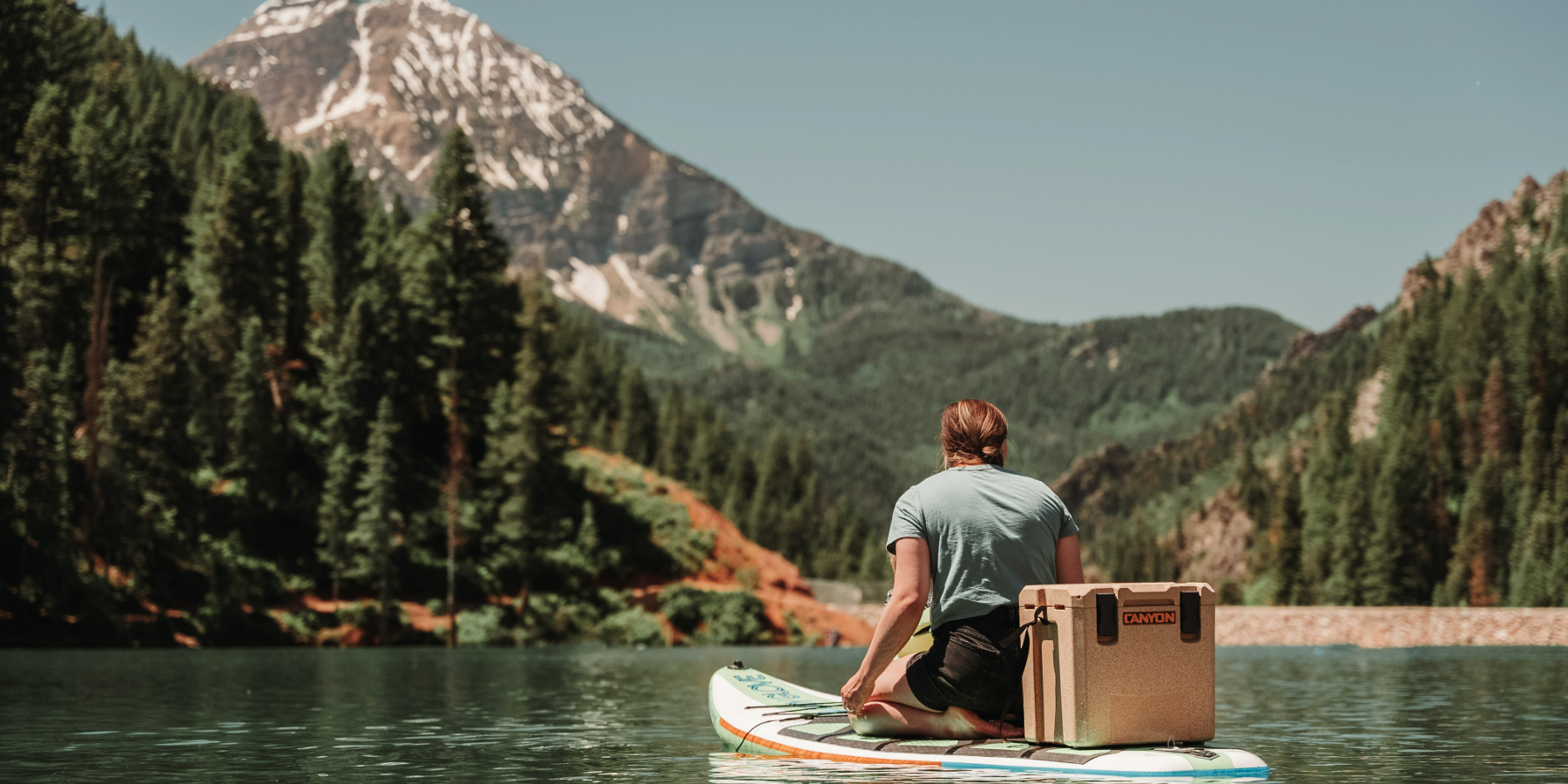 Labor Day Sale_Image of girl on paddleboard with Outfitter 22 V2 on a mountain lake